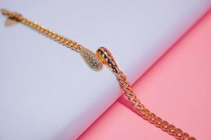 foto de uma pulseira de menina com um motivo de pêndulo pervertido em um fundo rosa