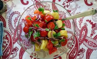 uma tigela com uma salada com cereja tomates, batatas, vermelho cebolas e manjericão. foto