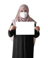 Mulher muçulmana usando máscara cirúrgica segurando um papel em branco sobre fundo branco foto