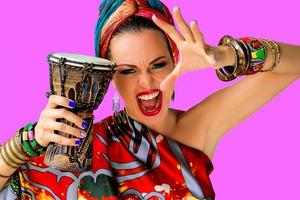 retrato de uma cantora jovem e atraente gritando em estilo africano com bateria em fundo colorido