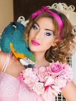 retrato de uma jovem mulher bonita em um vestido colorido com flores estilo boneca com ara no ombro foto