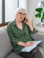 empresário sênior mulher amigável trabalhar em casa. falando ao telefone trabalhar com lap top. negócios, autônoma, conceito de mulher idosa foto