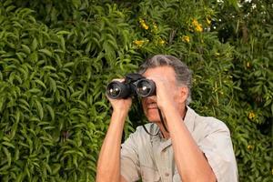 homem sênior do lado de fora curtindo a natureza olhando com binóculos foto