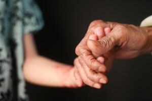 pequeno menina segurando mão do dela avó mão foto