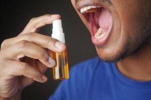 jovem homem aplicando fresco respiração spray foto