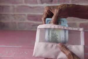 Senior mulheres mão salvando dinheiro dentro carteira. foto