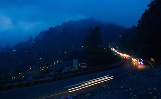 colorida noite luz trilhas em estrada com floresta fundo dentro punca bogor Indonésia foto