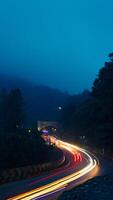 colorida noite luz trilhas em estrada com floresta fundo dentro punca bogor Indonésia foto