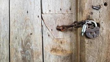 velho cadeado de metal vintage em uma porta de madeira fechada de uma antiga casa de fazenda. o verdadeiro estilo da aldeia. fechar-se. concentre-se no castelo. fundo de madeira, textura. copie o espaço