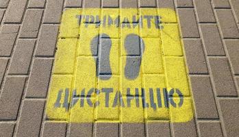 ucrânia, kiev - 23 de abril de 2020. calçada amarela com o aviso mantenha distância na calçada. o texto está em ucraniano. conceito de manter distância social, quarentena ou isolamento foto