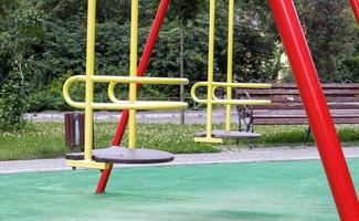 parque infantil moderno fechado. medidas de segurança e proteção contra covid-19 no parque da cidade. bebê vazio balanço de metal amarelo no parque sem pessoas. o conceito de infância acabou. foto