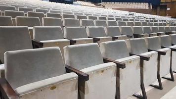 muitas cadeiras estofadas bege velhas sem pessoas no corredor para apresentações e filmes. fundo de muitas cadeiras nas arquibancadas em uma sala de concertos ou teatro. foto