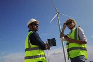 uma casal do elétrico engenheiros trabalhando juntos às uma vento turbina Fazenda. foto