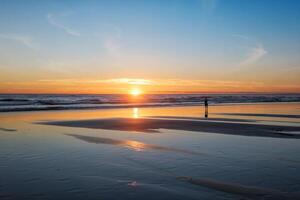 atlântico oceano pôr do sol com surgindo ondas às fonte da telha praia, Portugal foto