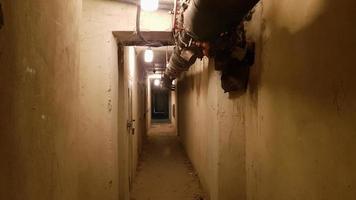 um porão escuro, um longo corredor com velhas portas e canos de metal enferrujado. túnel iluminado em um abrigo antiaéreo, bunker militar subterrâneo da guerra fria, perspectiva, colorido foto