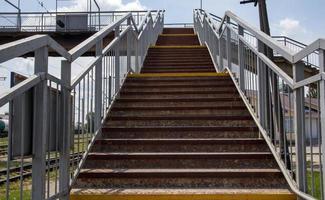 ponte ferroviária com degraus, com degraus impressionantes em perspectiva. passagem aérea de pedestres. escadas de ponte conectando uma plataforma a outra na estação de trem. foto