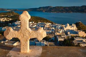 cristão Cruz e Plaka Vila em milos ilha sobre vermelho gerânio flores em pôr do sol dentro Grécia foto