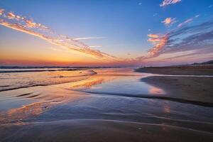 atlântico oceano pôr do sol com surgindo ondas às fonte da telha praia, Portugal foto