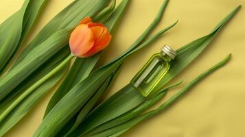 uma garrafa do verde óleo é colocada em a grandes folhas, com a laranja tulipa Próximo para isto. foto