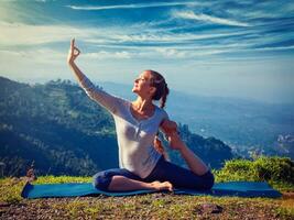 sorte em forma mulher fazendo ioga asana ao ar livre dentro montanhas foto