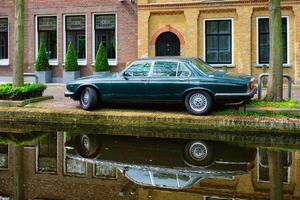 velho carro em canal aterro dentro rua do delft. Delft, Países Baixos foto