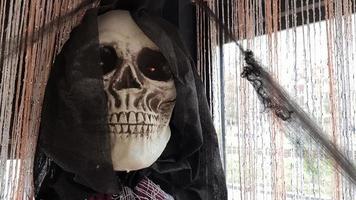 um retrato de um esqueleto com um capuz preto e uma teia de aranha em um interior decorado de forma festiva para o feriado de halloween.