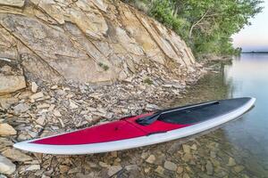 ficar de pé acima paddleboard em lago foto