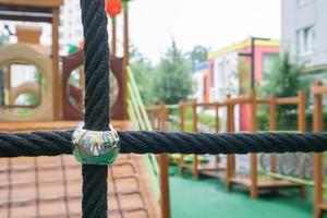 um pátio de prédios altos com um playground grande e moderno feito de madeira e plástico em um dia chuvoso de verão sem pessoas. playground ao ar livre vazio. um espaço para jogos e esportes infantis. foto