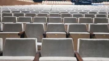 muitas cadeiras estofadas bege velhas sem pessoas no corredor para apresentações e filmes. fundo de muitas cadeiras nas arquibancadas em uma sala de concertos ou teatro. foto