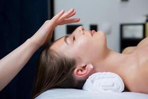 lindo jovem mulher obtendo facial massagem dentro spa salão. beleza tratamento conceito. foto