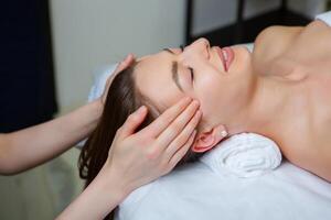 lindo jovem mulher obtendo facial massagem dentro spa salão. beleza tratamento conceito. foto