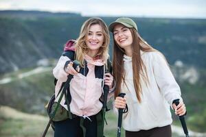 dois jovem mulheres caminhada dentro a montanhas e bebendo chá a partir de uma chaleira. viagem, viajante. foto