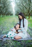 uma feliz família. mãe e filha descansar dentro a parque dentro vestidos foto