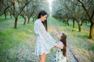 uma feliz família. mãe e filha descansar dentro a parque dentro vestidos foto