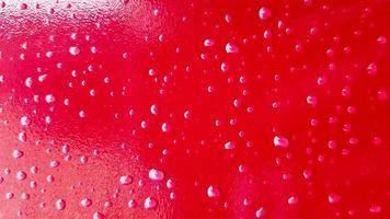 carro vermelho depois da chuva. gotas de água se acumulam no topo da superfície de metal. gotas de água vermelha em fundo abstrato foto