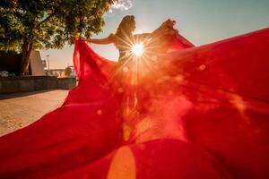 nascer do sol vermelho vestir. uma mulher dentro uma grandes vermelho vestir contra a pano de fundo do nascer do sol, brilhante dourado luz do a do sol raios. a conceito do feminilidade, harmonia. foto