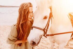 uma mulher dentro uma vestir carrinhos Próximo para uma branco cavalo em uma praia, com a azul céu e mar dentro a fundo. foto