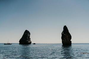 dois pedras bastão Fora do a água dentro a meio do a turquesa mar. cênico oceano Visualizações. Alto qualidade foto. gostar dentro Islândia foto