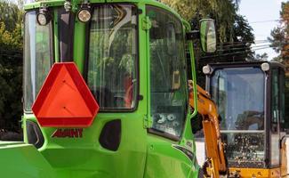 duas pequenas escavadeiras em um grande canteiro de obras. verde brilhante nas rodas e amarelo nas trilhas. terraplenagem e construção. escavadeira de pá. mini carregadores. ucrânia, kiev - 28 de agosto de 2021. foto