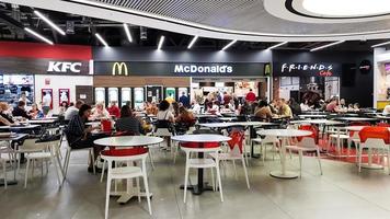 ucrânia, kiev - 6 de março de 2020. área de fast food com pessoas em um centro comercial e de entretenimento. mcdonald's e kfc. os visitantes e convidados do café comem fast food nas mesas do restaurante. foto