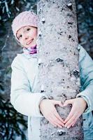 linda garota abraçando uma árvore na floresta foto