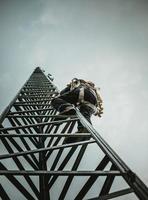 trabalhador de telecomunicações escalando torre de antena foto