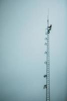 trabalhador de telecomunicações escalando torre de antena foto