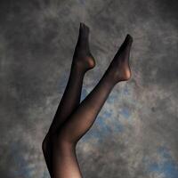 lindo mulher pernas em Sombrio fundo foto