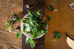 vegetariano salada a partir de uma misturar do fresco folhas dentro uma prato em uma de madeira fundo foto