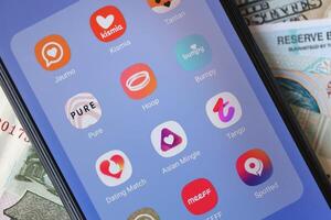Kyiv, Ucrânia - fevereiro 28, 2024 namoro apps ícones em Smartphone exibição e dinheiro contas foto