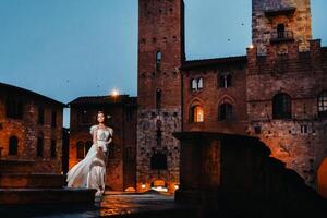 uma noiva dentro uma branco vestir dentro a velho Cidade do san gimignano.a menina anda em por aí a cidade dentro Itália.Toscana. foto