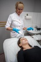 esteticista usa a darsonval dispositivo em a do cliente face. profissional pele Cuidado dentro a salão. a conceito do cosmetologia e rejuvenescimento. foto