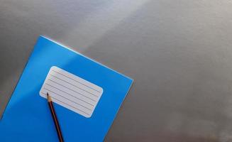 novo caderno azul com lápis sobre uma mesa cinza com raios de sol no fundo da janela foto