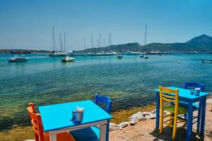 cafeteria mesa de praia dentro Adamantas Cidade em milos ilha com egeu mar com barcos dentro fundo foto